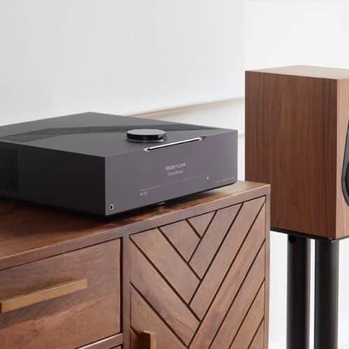 Schwarzer Verstärker und Lautsprecher auf Holzschrank.