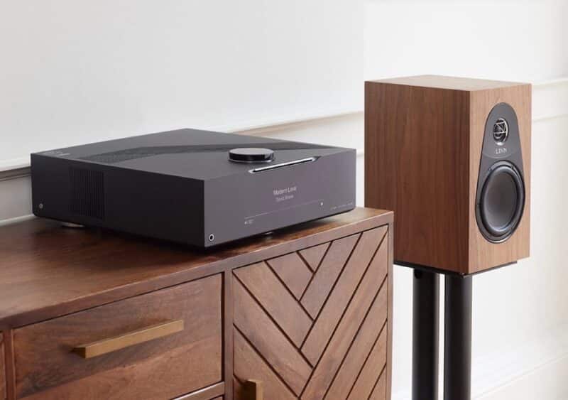 Schwarzer Verstärker und Lautsprecher auf Holzschrank.