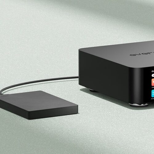 Schwarzes Audiogerät mit Kabel und Bildschirm auf Tisch.