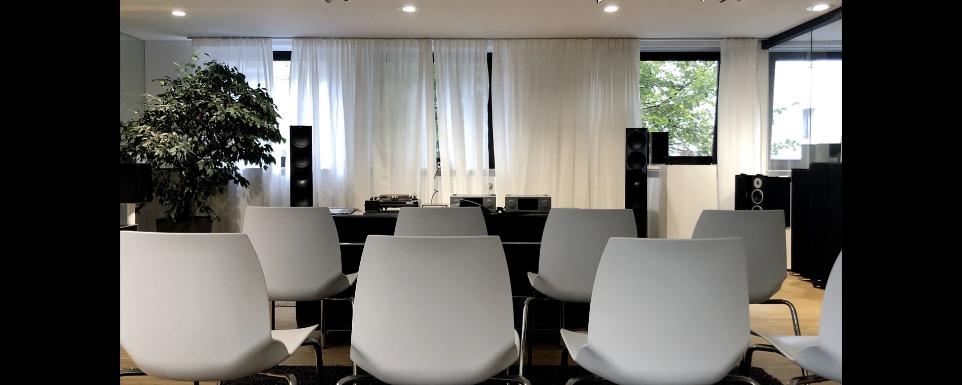 Moderner Konferenzraum mit weißen Stühlen und Lautsprechern